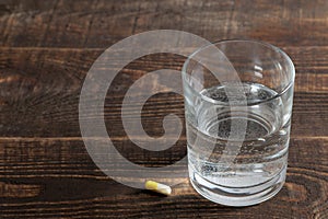 Depression concept. a glass with water and a tablet on a wooden brown table. place for text