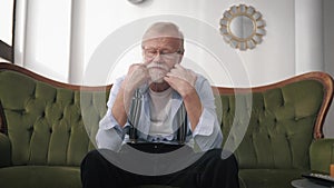 Depression, an old pensioner with a beard and glasses for vision suffers and is sad because of life difficulties sitting