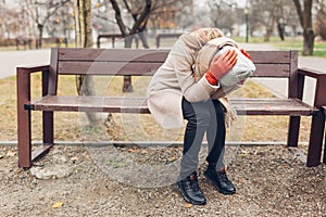 Depression. Upset young woman sitting on bench in autumn park crying covering face with hands. Mental health