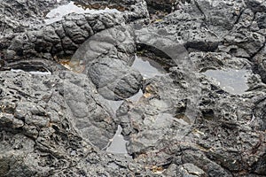 Depressions in a rock with white sand at the bottom, flooded with sea water. Small ponds excavated in lava bed on Indian Ocean