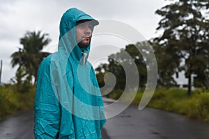 Depressive concept with lonely man in raincoat standing on wet road under rain close up isolated