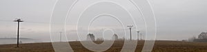 Depressive, ghostlike and foggy winters day in Czech countryside. Meadow with electric posts in the fog photo