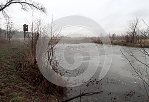 Depressive, ghostlike and foggy winters day in Czech nature. Panorama of a meadow with frosted pond in the foreground.