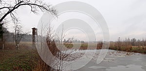 Depressive, ghostlike and foggy winters day in Czech nature. Panorama of a meadow with frosted pond in the foreground