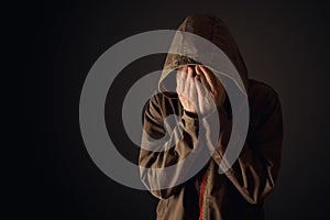 Depressive man in hooded jacket is crying