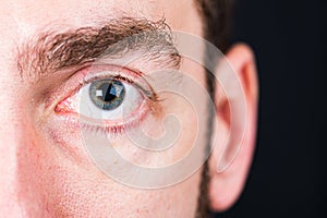 Depth of field - focus on eye of man with unsharped ear on the black background