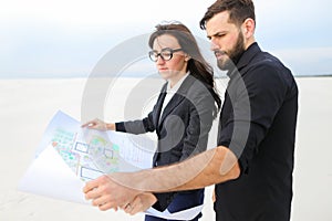 Deputy female and architect male with whatman paper discussing