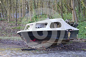 Derelict abandoned fibreglass boat on trailer dumped in waste ground