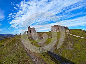 Derelict castle walls on top of grassy hill in Wales