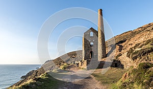 Derelict Cornish tin mine, on the cliff edge, against a blue sky