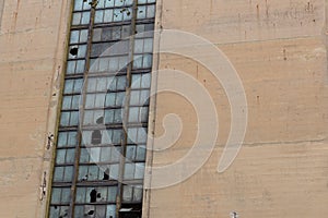 Derelict industrial building wall with broken out wire glass windows in metal frames, copy space