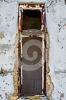 Derelict metal window frame set into a delapidated block wall