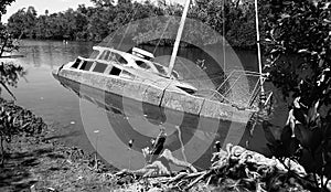 Derelict partially sunken weathered hull of a white motor yacht