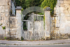 Derelict wooden gate in an old textured stone wall.