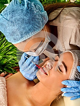 Dermal fillers of woman in spa salon with beautician.