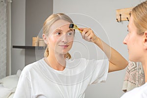 Dermaroller. Woman is making procedure on face with meso roller in home photo