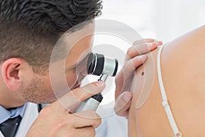 Dermatologist checking mole on woman