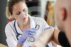 Dermatologist conducts medical examination on skin of male patient with magnifying glass in clinic.