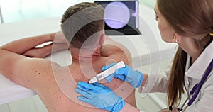 Dermatologist examines birthmarks on patient skin using digital dermatoscope