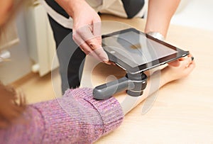 dermatologist examines moles on a female patient& x27;s arm with a dermatoscope and a computer tablet. Prevention of