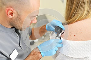 dermatologist examines neoplasms on the patient& x27;s skin using a special dermatoscope device. Prevention of melanoma.