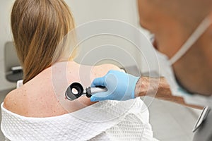 dermatologist examines neoplasms on the patient& x27;s skin using a special dermatoscope device. Prevention of melanoma.