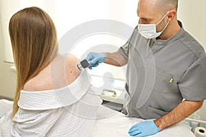dermatologist examines neoplasms on the patient& x27;s skin using a special dermatoscope device. Prevention of melanoma.