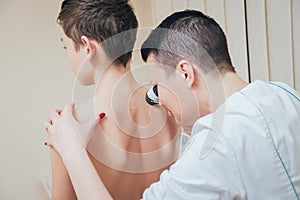 Dermatologist examines patient birthmark with dermatoscope. Medical equipment