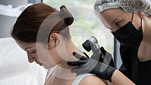 A dermatologist examines a patient& x27;s mole through a dermatoscope.