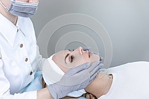 A dermatologist examines the skin and pimples on the patient& x27;s face