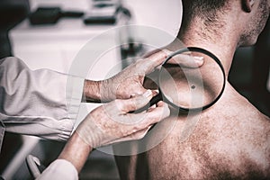 Dermatologist examining mole with magnifying glass