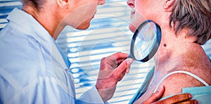 Dermatologist examining mole with magnifying glass