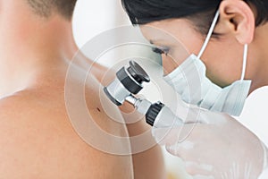 Dermatologist examining mole on patient