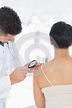 Dermatologist examining mole on woman