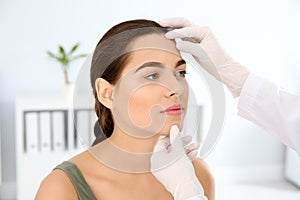 Dermatologist examining patient`s face in clinic.