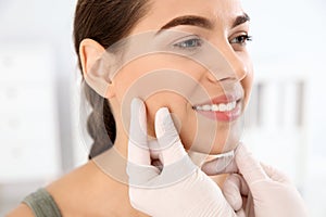 Dermatologist examining patient`s face in clinic.