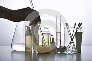 Dermatologist formulating and mixing pharmaceutical skincare, Cosmetic blank bottle containers and scientific glassware.