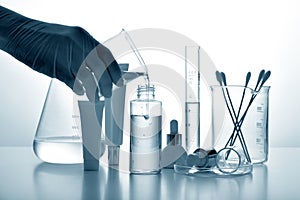 Dermatologist formulating and mixing pharmaceutical skincare, Cosmetic bottle containers and scientific glassware.