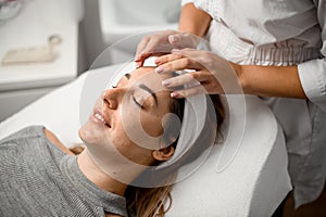 Dermatologist makes a facial massage for a girl with acne with a smile on face