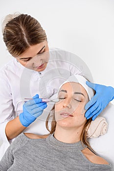 Dermatologist makes a salon procedure on a face of a woman lying on a couch