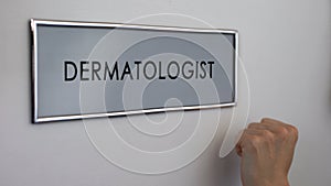Dermatologist room door, patient hand knocking closeup, skin health examination