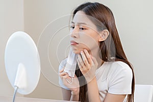 Dermatology, puberty asian young woman, girl looking into mirror, allergy when wear mask and cosmetic, show squeezing pimple spot