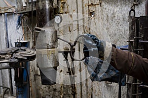 Derrick. The assistant driller pulls the drill pipe with a hook in protective gloves. Safety in the drilling of oil and gas wells