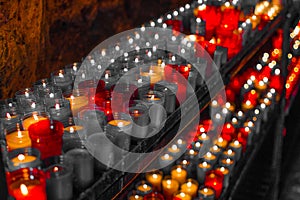 Desaturated red close up of colorful candles in a dark spiritual scene. Commemoration, funeral, memorial. Religious symbolism photo