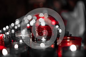 Desaturated red image of a closeup of colorful candles burning in the tunnel of Covadonga, Cangas de Onis, Asturias, Spain.