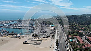 descending aerial footage of West Beach with boats and yachts docked in the marina, cars driving on the street