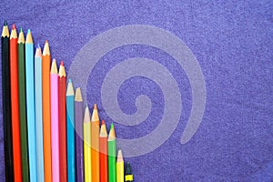 A descending chart of colorful, bright, variegated drawing pencils, a notebook