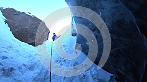 Descent into a deep ice cave. The climber descends