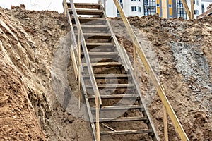 Descent into a deep pit during the construction of the building. Safety in construction. Ladder for descending to reinforced