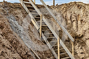 Descent into a deep pit during the construction of the building. Safety in construction. Ladder for descending to reinforced